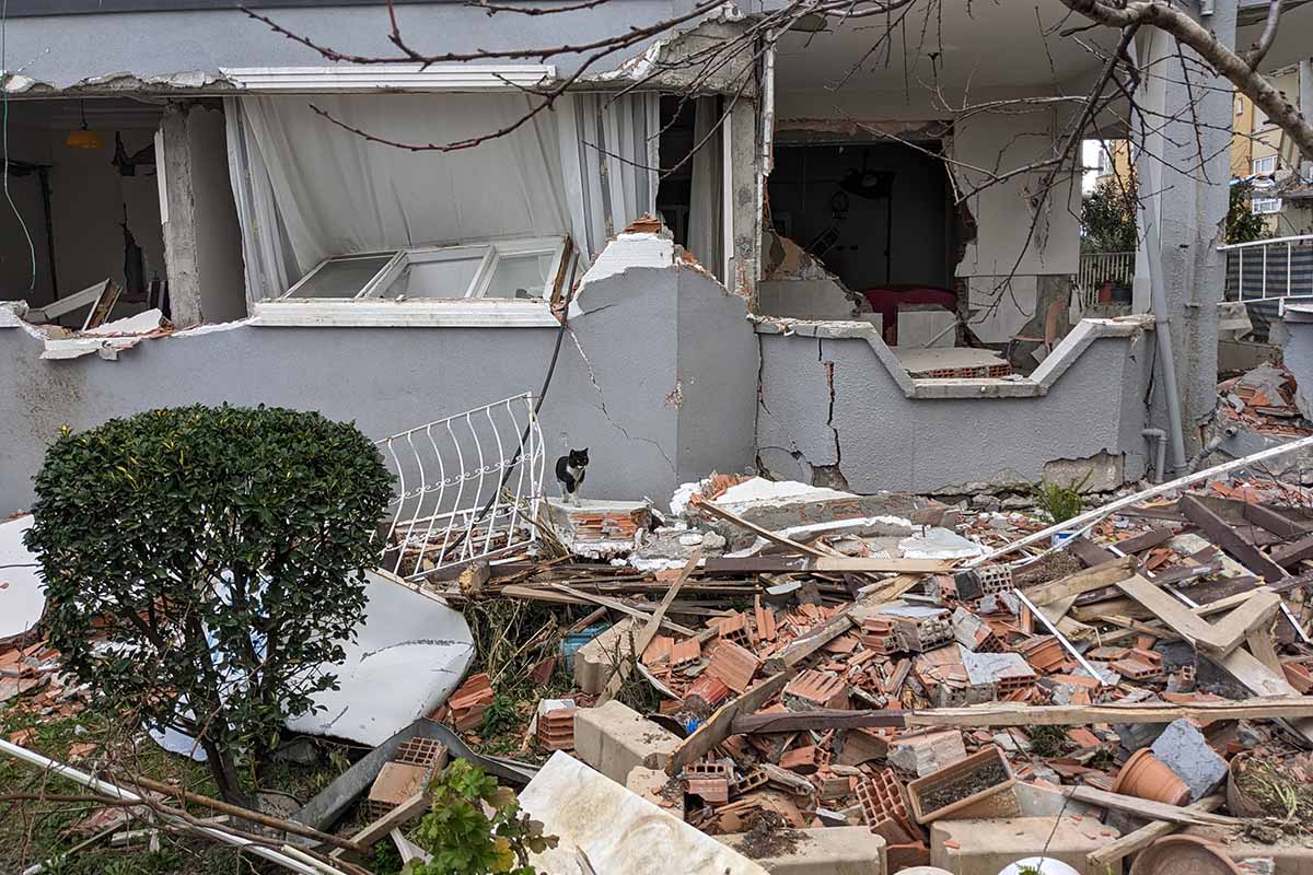 Ein von Erdberben zerstoertes Haus. Truemmer liegen im Garten.