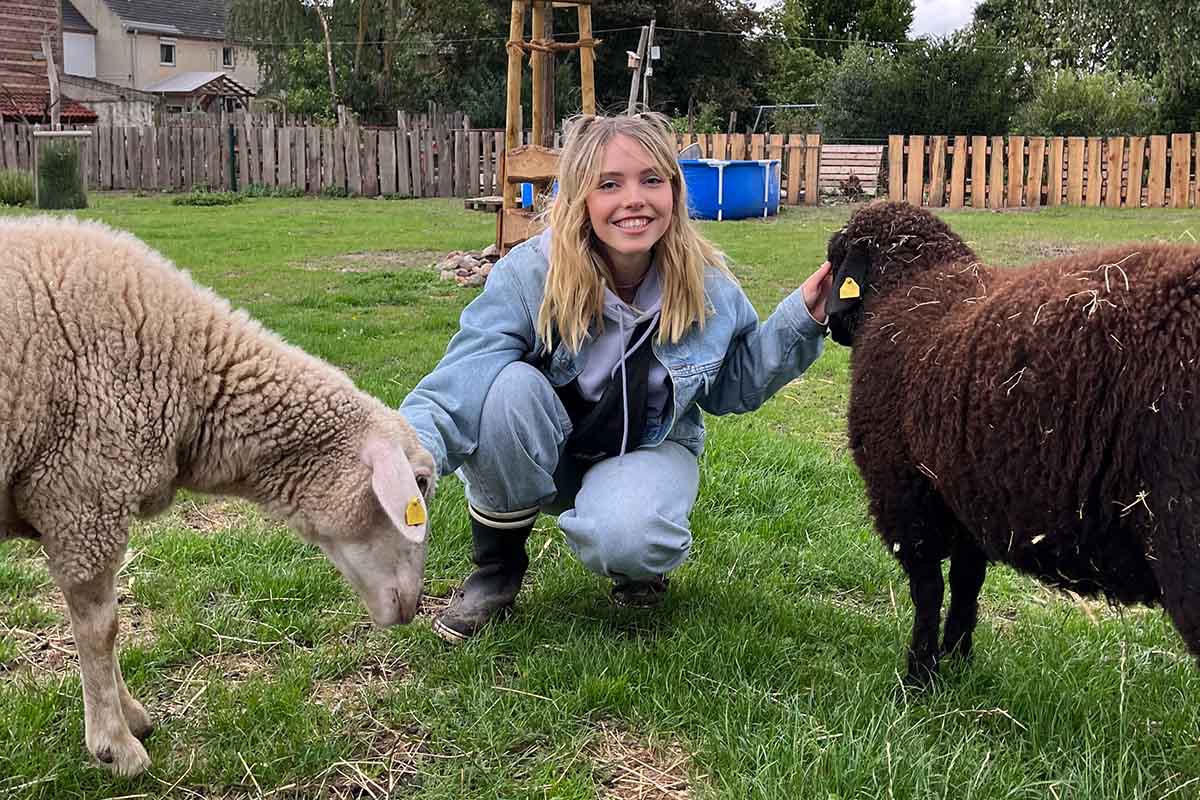 Eine Frau mit einem hellen und dunklen Schaf.