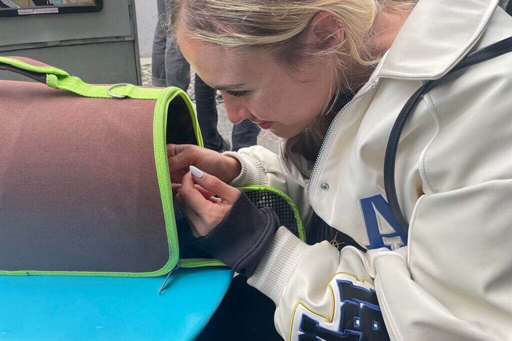 Alena Gerber lächelt in eine Hundebox