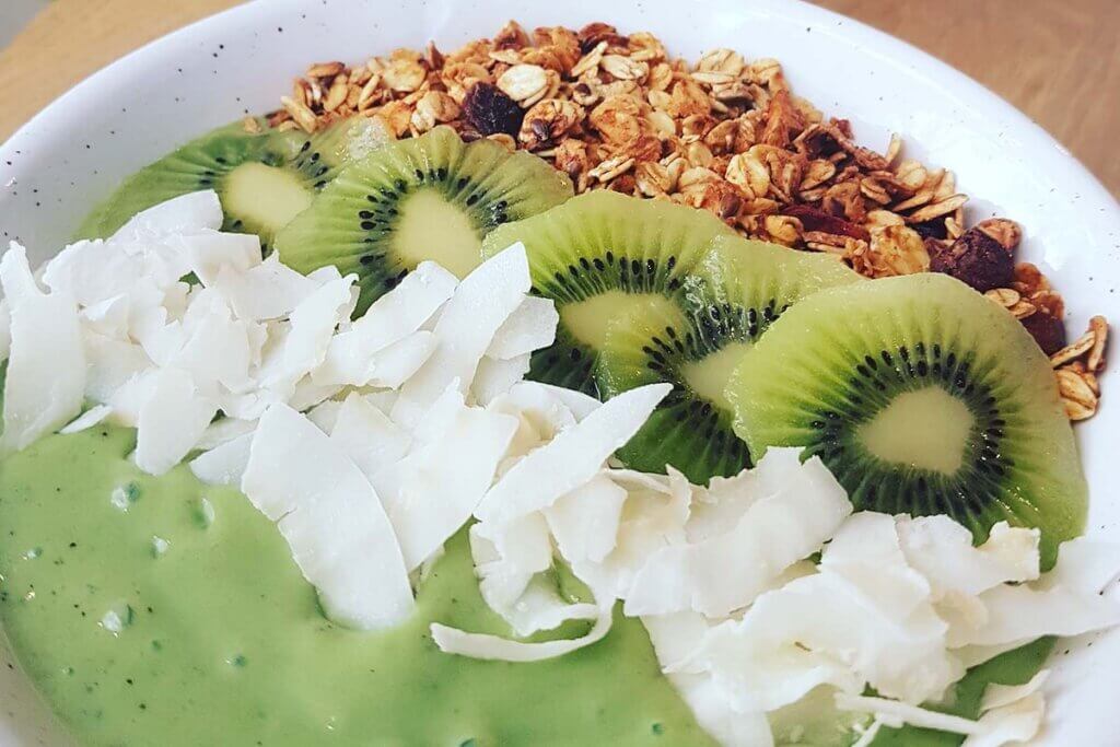 Eine vegane Smoothie Bowl, angerichtet in einer weissen Schuessel.