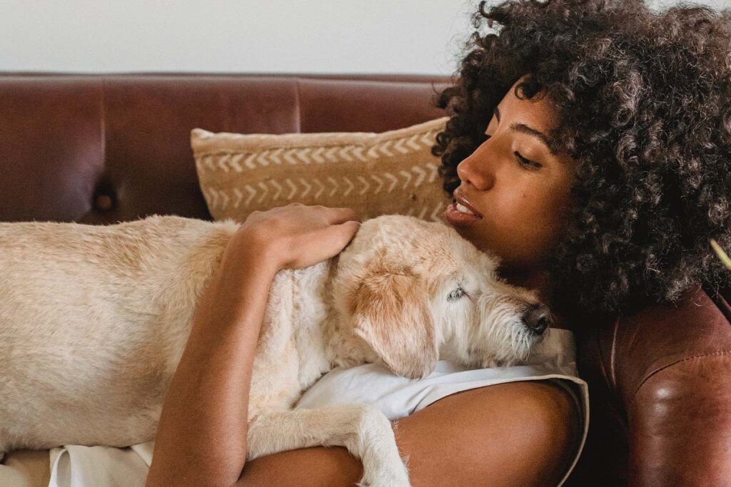 Eine Frau kuschelt mit ihrem Hund auf dem Sofa.