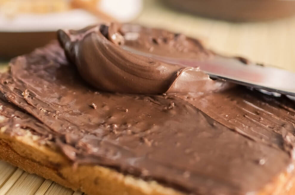 Ein Toast mit veganem Schokoaufstrich auf dem ein Messer liegt.